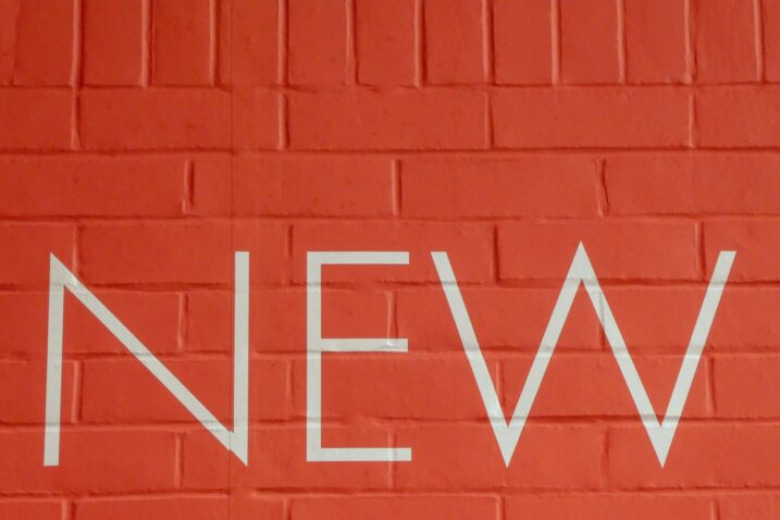 Brick wall painted red. Reads 'NEW' in all caps.